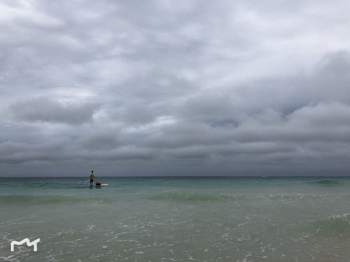 著名的白沙滩海边，海上的人站在一块板上划行，你可以叫他过来载你游玩，不过要付钱的