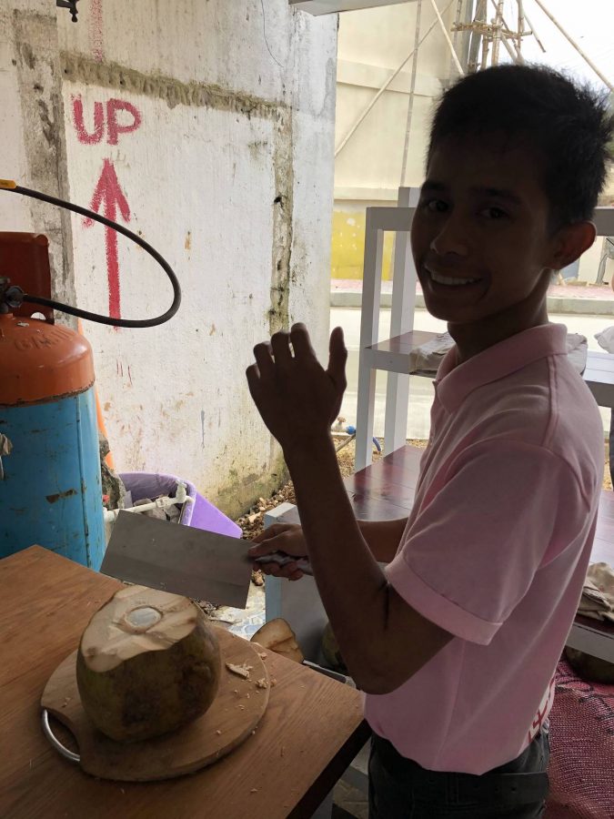 店里的服务员，让他摆个姿势拍照片，他在给我们切椰子